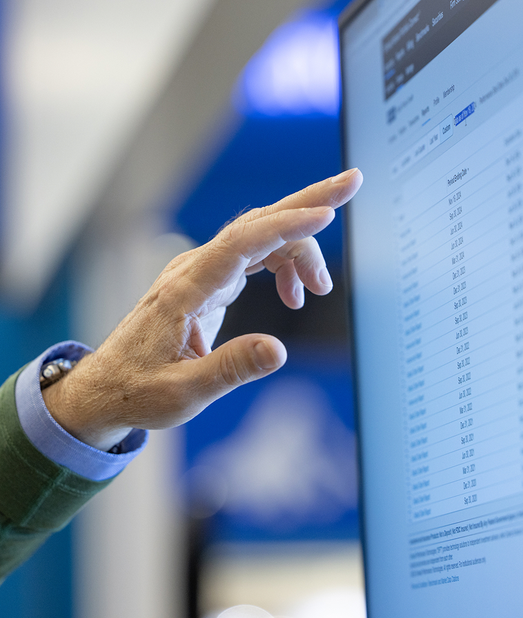Close-up of hand pointing at information on screen.