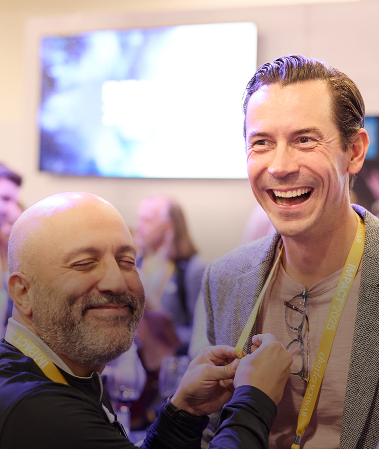 Two attendees sharing a laugh at IMPACT 2025.