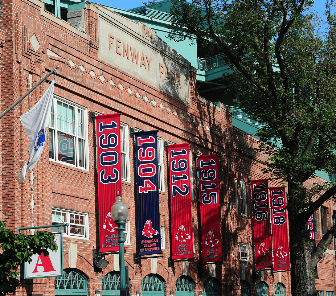Brick exterior of Fenway Park with championship banners hanging along the facade.