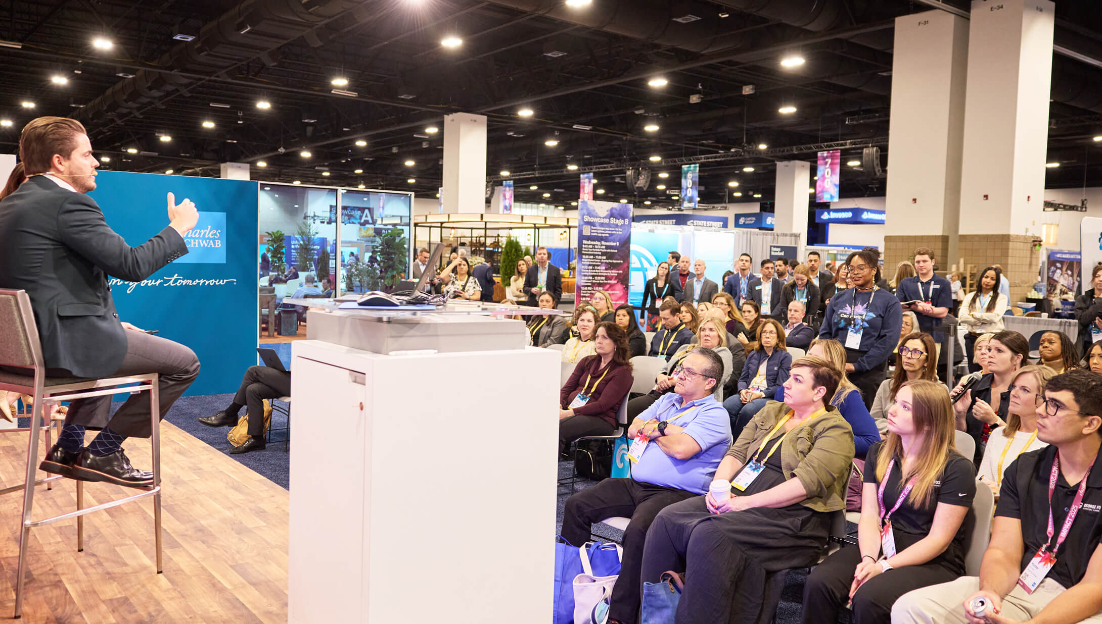 Education session audience listening to a man seated onstage speaking in The Exchange at IMPACT 2025.
