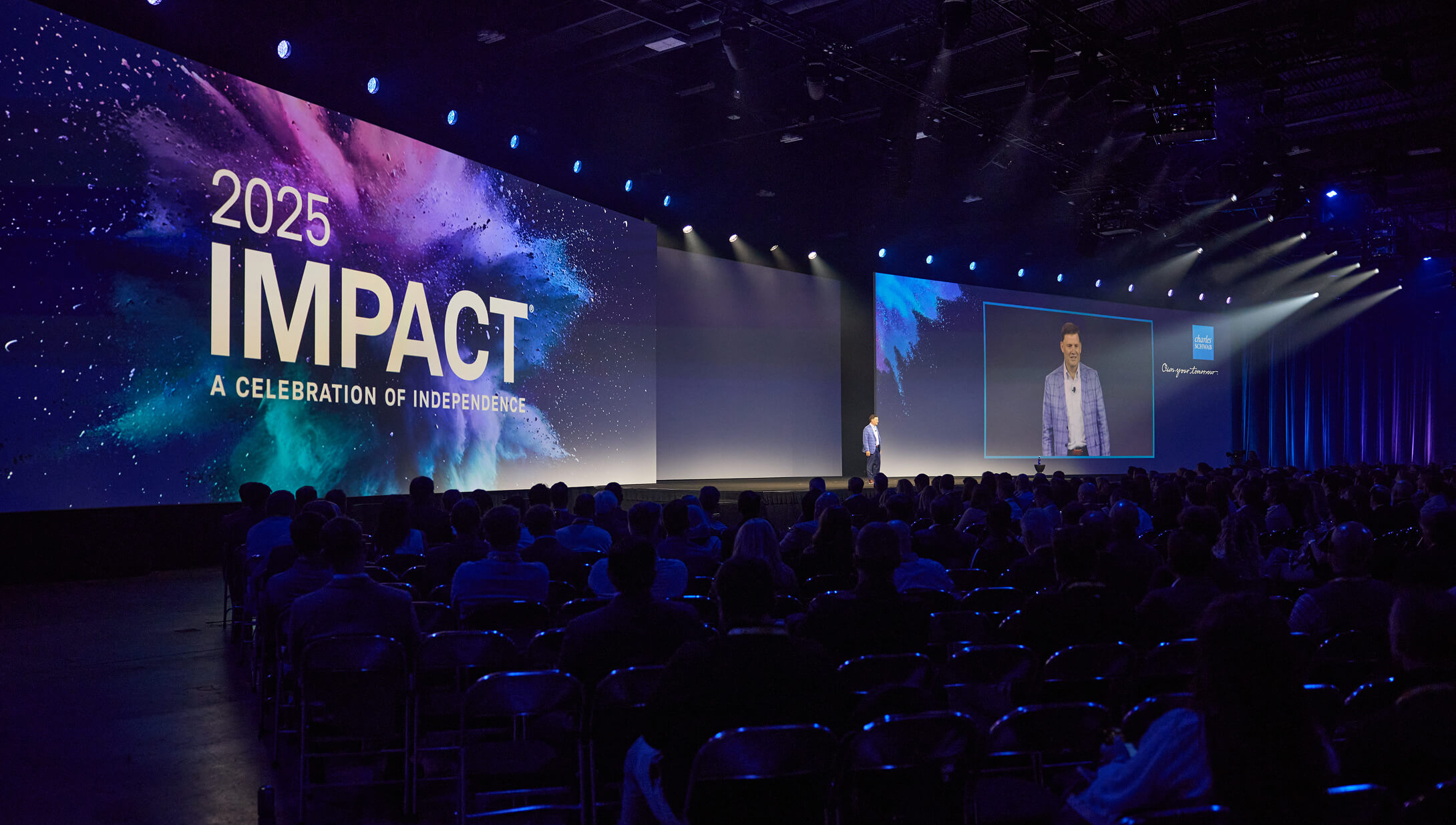 Audience in a dark room watching Jonathan S. Beatty, managing director and head of Schwab Advisor Services, on stage in front of an IMPACT 2025 backdrop.