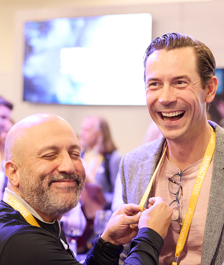Two attendees sharing a laugh at IMPACT 2025.