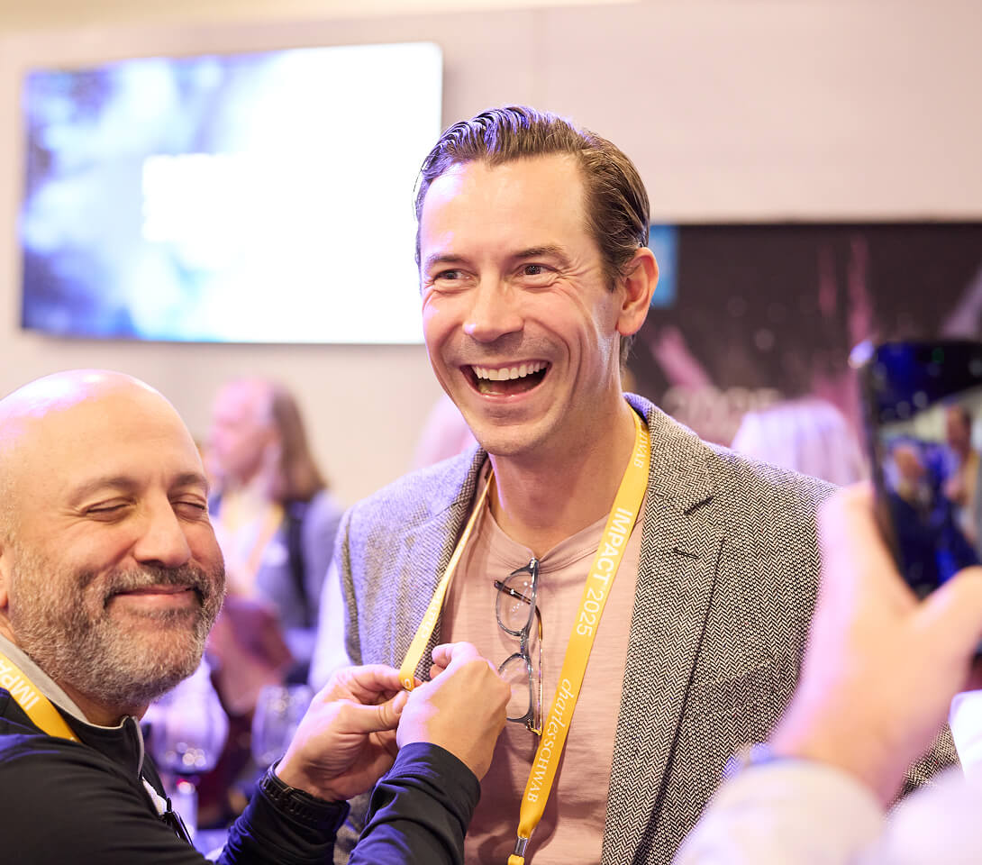 Two attendees sharing a laugh at IMPACT 2025.