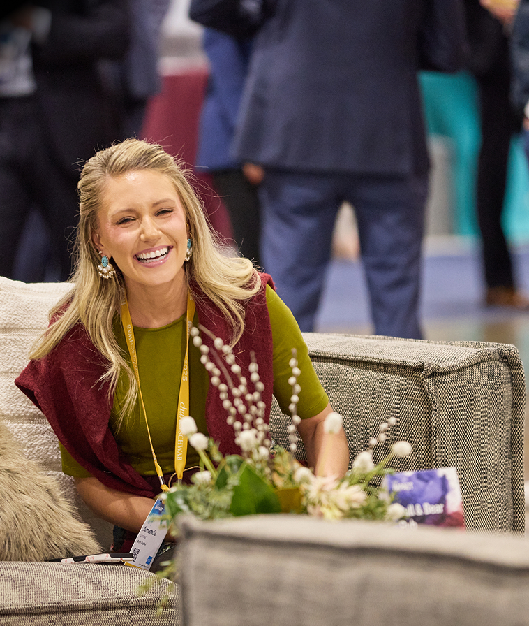 Smiling woman attendee seated in The Exchange at IMPACT 2025.