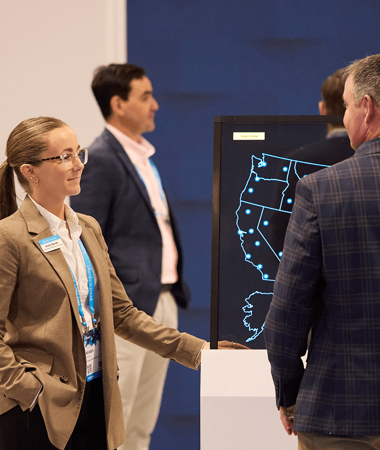Attendees near a digital map display in The Exchange at IMPACT 2025.
