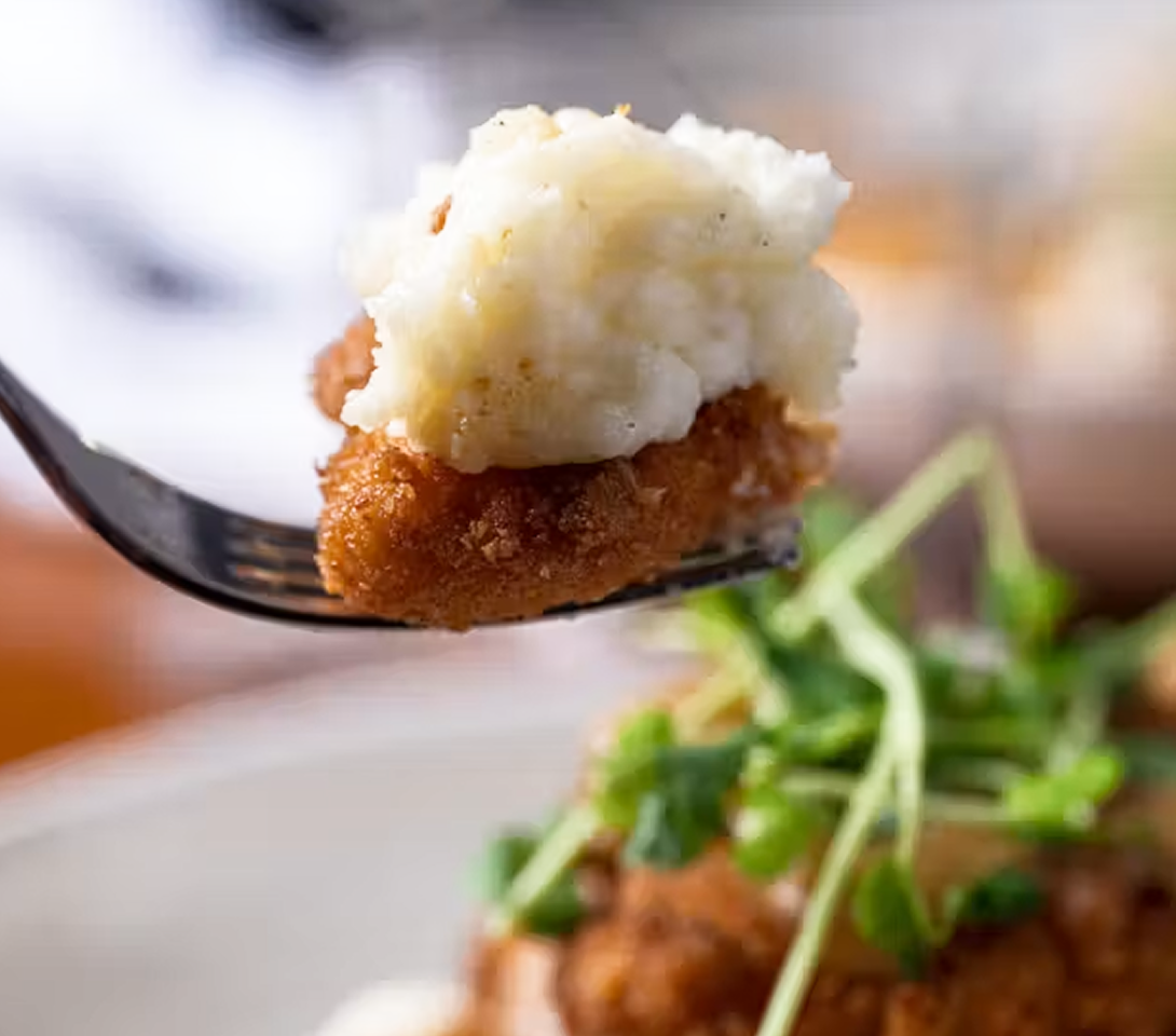 Forkful of Ritz Cracker Crusted Chicken with whipped potatoes, onion butter, pepper jam, and chow chow, from Stillwater in Boston.