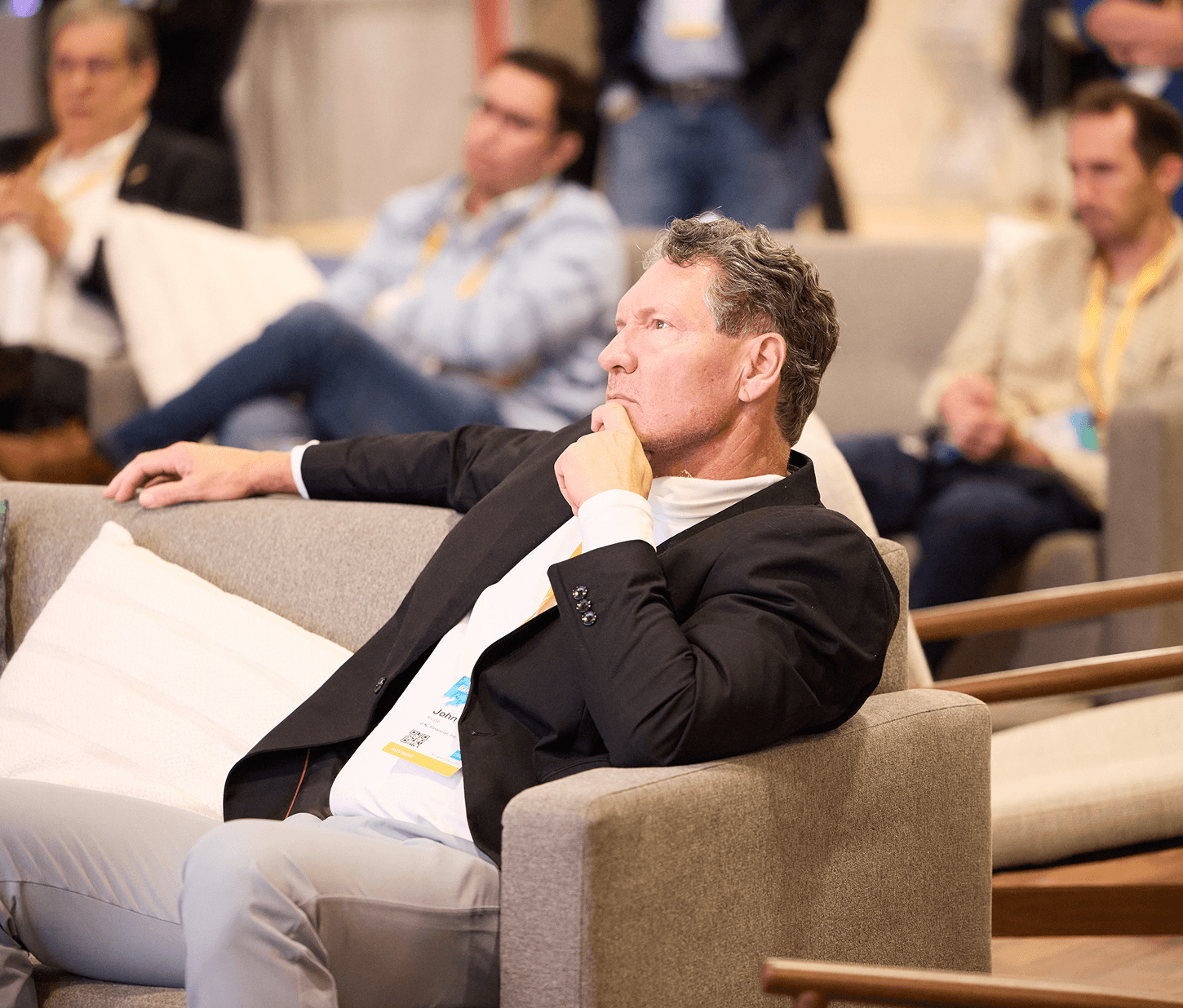 IMPACT 2025 attendee in lounge seating, chin in hand, listening to a speaker.