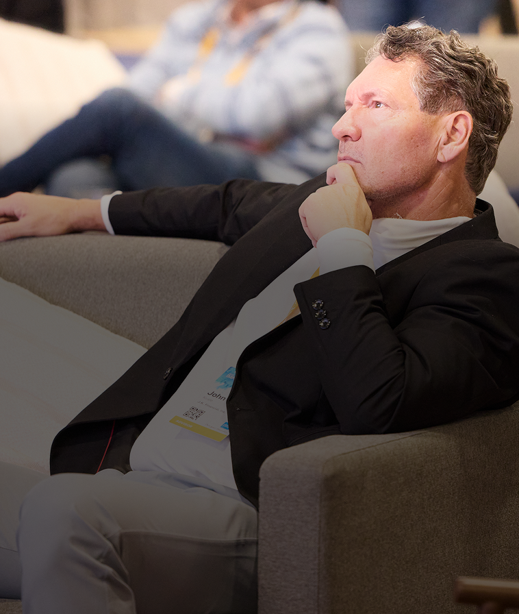 IMPACT 2025 attendee in lounge seating, chin in hand, listening to a speaker.