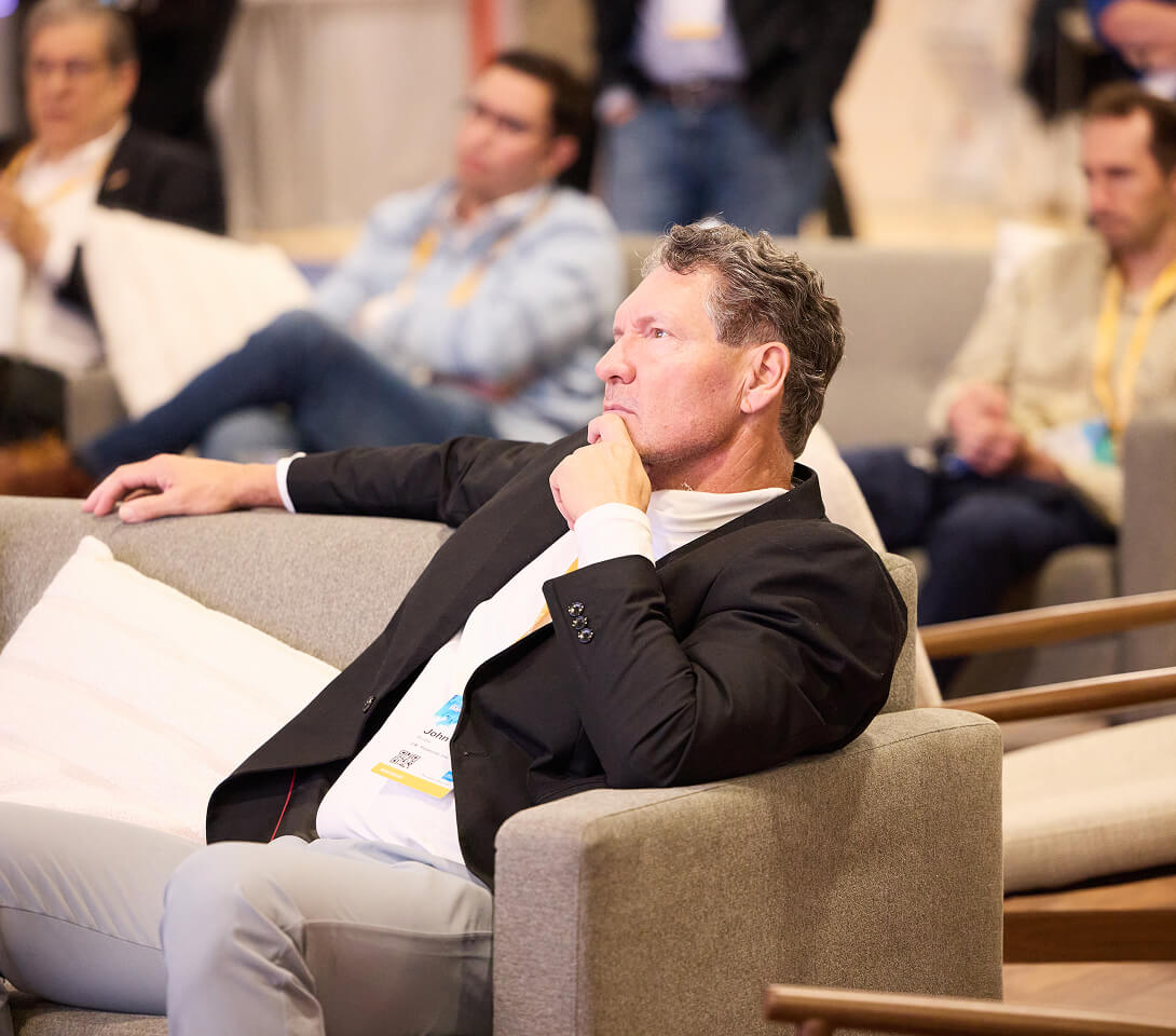 IMPACT 2025 attendee in lounge seating, chin in hand, listening to a speaker.